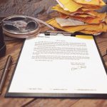 A signed document on a clipboard beside a pen