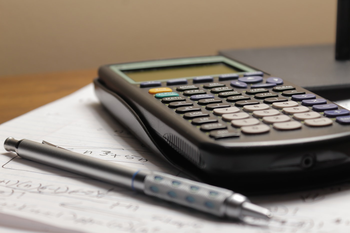 A calculator and pen resting on printed paperwork